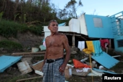 Ramon Sostre, stands in front of his damaged house after Hurricane Maria destroyed the town's bridge in San Lorenzo, Morovis, Puerto Rico, Oct. 4, 2017.