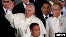 Paus Fransiskus melambai kepada massa didampingi Presiden Filipina Benigno Aquino saat tiba di Manila, Kamis (15/1).