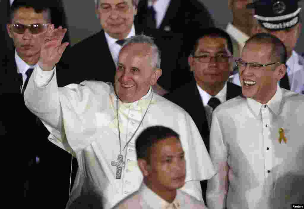 Pope Francis waves to the crowd beside Philippines' President Benigno Aquino upon his arrival at Villamor Air Base for a state and pastoral visit, in Manila, Jan. 15, 2015.