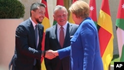 King Abdullah II (C) greets German Chancellor Angela Merkel as she shakes hands with Crown Prince Hussein at the Royal Palace in Amman, Jordan, June 21, 2018.