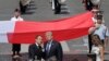 French President Emmanuel Macron talks with President Donald Trump next to a huge French flag after the Bastille Day parade in Paris, July 14, 2017. 