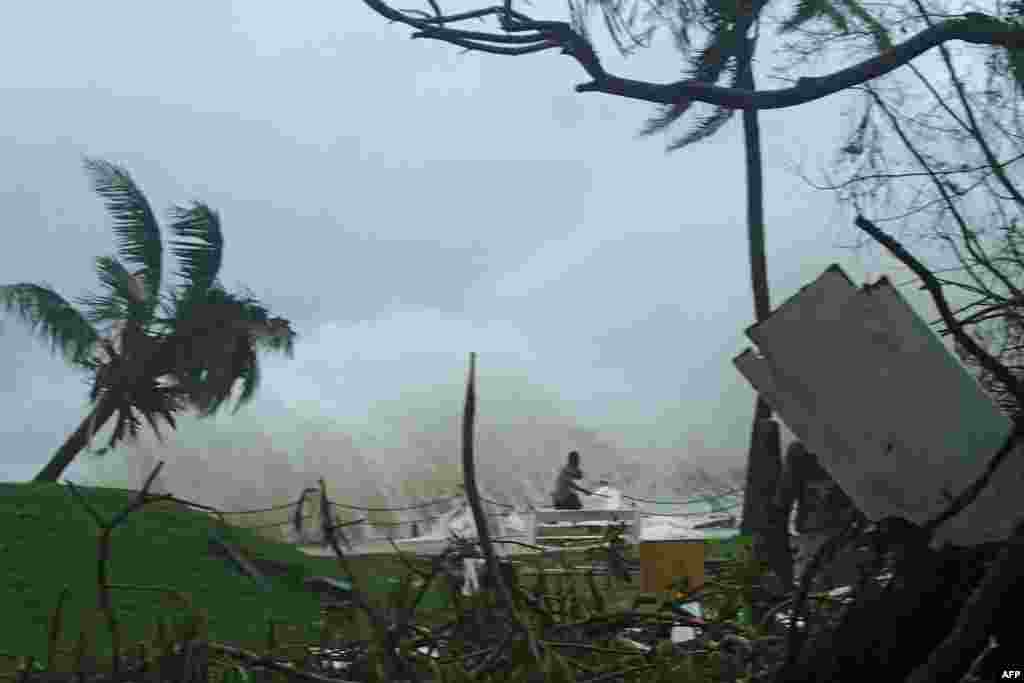 This handout photo received on March 15 by CARE Australia shows a man running away from high waves caused by Cyclone Pam crashing along the coast in Port Vila.