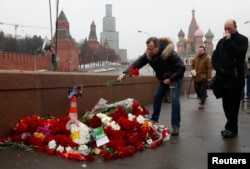 People come to lay flowers at the site, where Boris Nemtsov was shot dead, with St. Basil's Cathedral (R) and the Kremlin walls seen in the background, in central Moscow, February 28, 2015.
