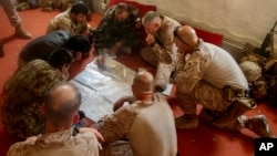 FILE - A photo released by Operation Resolute Support headquarters shows U.S. Marines with Task Force Southwest and Afghan National Army soldiers planning for the continuation of offensive combat operations at Camp Hanson, Afghanistan, June 13, 2017. 