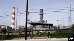 A jogger runs past the Scattergood power plant, Feb. 12, 2019, in Los Angeles. Los Angeles will abandon a plan to spend billions rebuilding three natural gas power plants as the city moves toward renewable energy, Mayor Eric Garcetti said Monday.