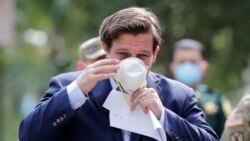 Florida Gov. Ron DeSantis puts on a protective face mask during a news conference at the Urban League of Broward County, during the new coronavirus pandemic, Friday, April 17, 2020, in Fort Lauderdale, Fla. (AP Photo/Lynne Sladky)