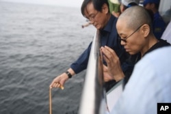 In this photo provided by the Shenyang Municipal Information Office, Liu Xia, the wife of Chinese Nobel Peace Prize laureate Liu Xiaobo, watches as Liu's ashes are buried at sea off the coast of Dalian in northeastern China's Liaoning Province, July 15, 2017.
