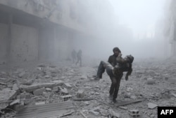 FILE - A wounded man is carried following an air strike on the rebel-held besieged town of Arbin, in the eastern Ghouta region on the outskirts of the capital Damascus on January 2, 2018.