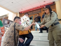 Warga yang mengurus administrasi kependudukan diminta mencuci tangan dengan hand sanitizer yang disediakan Pemkot Solo, Senin, 16 Maret 2020. (Foto: Humas Pemkot Surakarta)