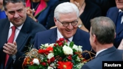 German president-elect, Frank-Walter Steinmeier, receives flowers after the first round of voting of the German presidential election at the Reichstag in Berlin, Feb. 12, 2017.
