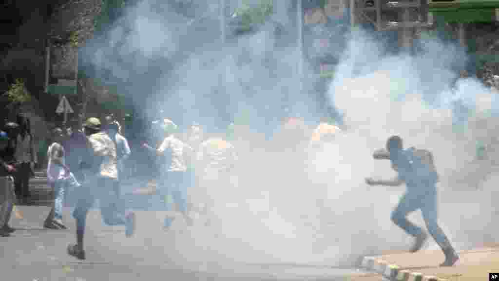 University students run as police use tear gas to disperse them during a demonstration in Nairobi, Kenya, Tuesday, Sept, 22, 2015.