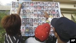 A Cambodian man compares a photo to those of stampede victims at Preah Kossamak Hospital in Phnom Penh, Cambodia, 24 Nov 2010