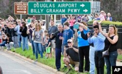 People take photos as the hearse carrying the body of Billy Graham drives toward the Billy Graham Library in Charlotte, N.C., Feb. 24, 2018. Graham's body was brought to his hometown of Charlotte on Saturday as part of a procession expected to draw crowds of well-wishers.