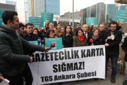 FILE - Turkish journalists hold a banner reading "Journalism doesn't fit in the card" as they protest the Turkish government cancelling press cards of journalists working for opposition dailies Evrensel and BirGun, in Ankara, Jan. 27, 2020.