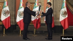 Outgoing leader Felipe Calderon (L) hands the national flag to Mexico's new president, Enrique Pena Nieto, during a midnight ceremony at the National Palace in Mexico City, Dec. 1, 2012. 