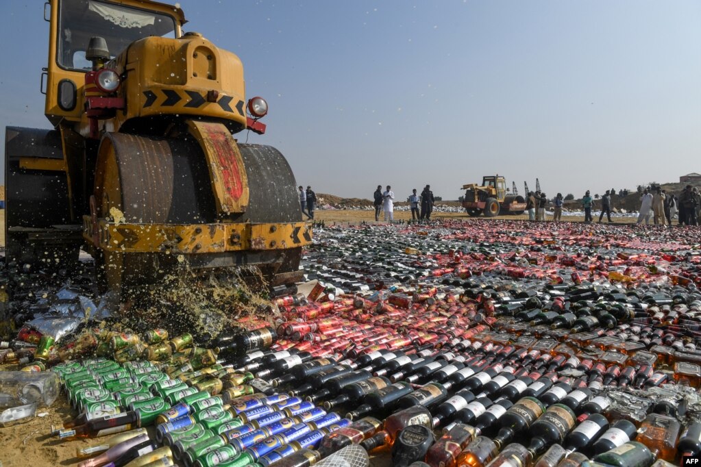 An official uses a steamroller to crush seized bottles of liquor, which had been smuggled into the country, on the outskirts of Karachi, Pakistan.