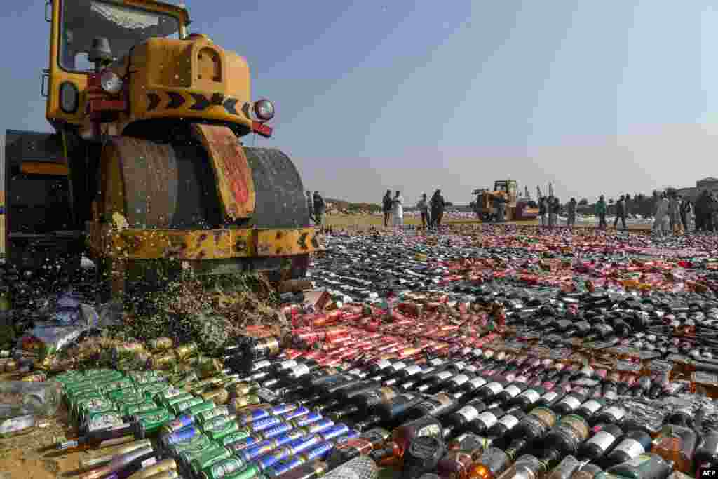 An official uses a steamroller to crush seized bottles of liquor, previously smuggled into the country, on the outskirts of Karachi. 