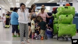 FILE - Passengers wait in line for a flight at Miami International Airport in Miami, Florida, Sept. 27, 2012.