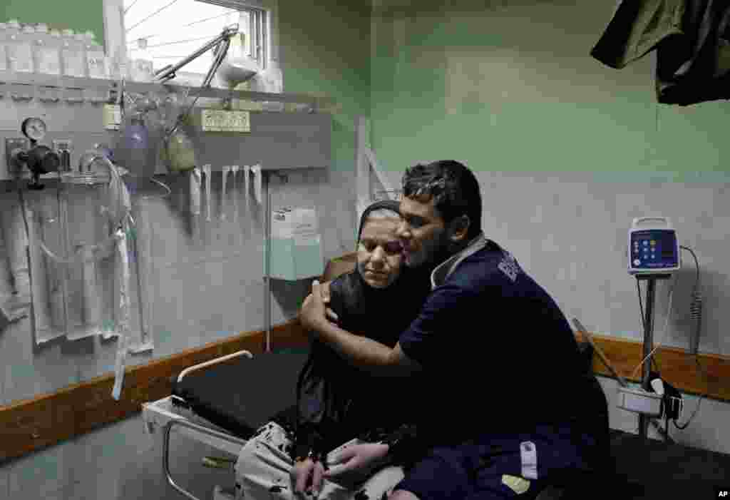 A Palestinian comforts a woman, wounded in an Israeli strike at a house in Beit Lahiya, northern Gaza Strip, at the emergency room of the Kamal Adwan Hospital, in Beit Lahiya.
