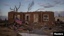 A US flag is tied to a fallen tree in front of a destroyed residence in the aftermath of a tornado in Mayfield, Ky.,Dec. 14, 2021.