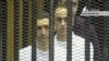 This video image taken from Egyptian State Television shows the sons of Hosni Mubarak, Alaa Mubarak, left and Gamal Mubarak as they stand inside the cage of mesh and iron bars in a Cairo courtroom Wednesday Aug. 3, 2011 as his historic trial began on c
