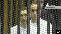 This video image taken from Egyptian State Television shows the sons of Hosni Mubarak, Alaa Mubarak, left and Gamal Mubarak as they stand inside the cage of mesh and iron bars in a Cairo courtroom Wednesday Aug. 3, 2011.