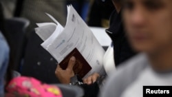 Un migrante venezolano sostiene su pasaporte en una fila para obtener un permiso de residencia temporal frente a la oficina de inmigración en Lima,, el 31 de octubre de 2018. 