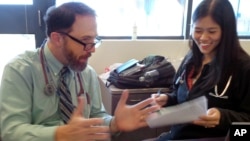 In this Wednesday, Sept. 23, 2015 photo, Dr. Rick Sacra reviews patient cases with Dr. Anna Chon at the Family Health Center in downtown Worcester, Mass., where he advises doctors in training. 