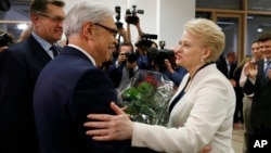Lithuania's Prime Minister Algirdas Butkevicius (L) and center-left presidential candidate Zigmantas Balcytis (C) congratulate President Dalia Grybauskaite after her winning the presidential election in Vilnius, Lithuania, May 26, 2014. 