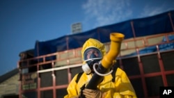 A health worker stands in the Sambadrome as he sprays insecticide to combat the Aedes aegypti mosquitoes that transmit the Zika virus, in Rio de Janeiro, Brazil, Tuesday, Jan. 26, 2016.