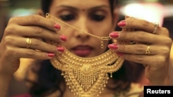 A salesgirl shows a gold necklace to customers at a jewelery showroom in the northern Indian city of Chandigarh, November 11, 2012. 