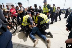 FILE - A man is detained while white supremacist Jason Kessler arrives at the Vienna metro station in Vienna, Va., Aug. 12, 2018. White nationalists are gathering in Washington on the first anniversary of their rally in Charlottesville.