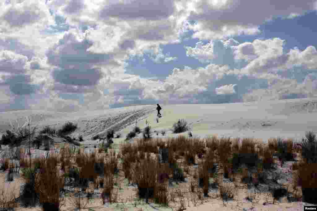 Seorang perempuan tampak berjalan di kawasan Monumen Nasional White Sands dekat Alamogordo, negara bagian New Mexico, Amerika tanggal 6 Oktober 2015. Taman itu terdiri dari bukit-bukit berpasir putih yang terbuat dari butiran gipsum. Ini adalah ladang pasir gipsum terbesar di dunia.