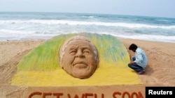 L’artiste Sudarshan Pattnaik travaillant sur une sculpture de sable géante à l'image de l'ancien président sud-africain Nelson Mandela, pour lui souhaiter un prompt rétablissement, Puri, Inde, 9 juin 2013. 