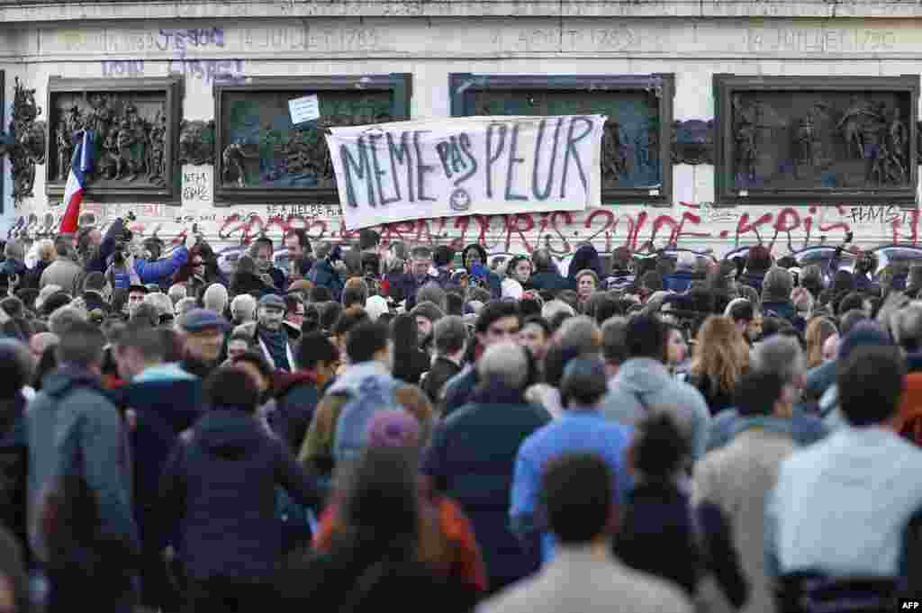 A banner reading 'Not afraid' is seen as people gather around the Monument a la Republique, at the Place de la Republique in Paris, on Nov. 15, 2015, two days after a series of deadly attacks. 