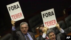 Deputies from opposition parties carry signs that read in Portuguese "Temer Out," during a key vote by the lower chamber of Brazil's Congress on whether to suspend Brazil's President Michel Temer and put him on trial over an alleged bribery scheme, in Bra