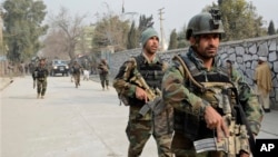 FILE - Afghan security forces patrol the site of a deadly suicide attack in Jalalabad, east of Kabul, Afghanistan, Jan. 24, 2018. The country plans to add 36,000 men to augment its existing forces with a contingent that would be charged with defending areas military-led operations have cleared of Taliban insurgents, but some see the initiative as controversial.