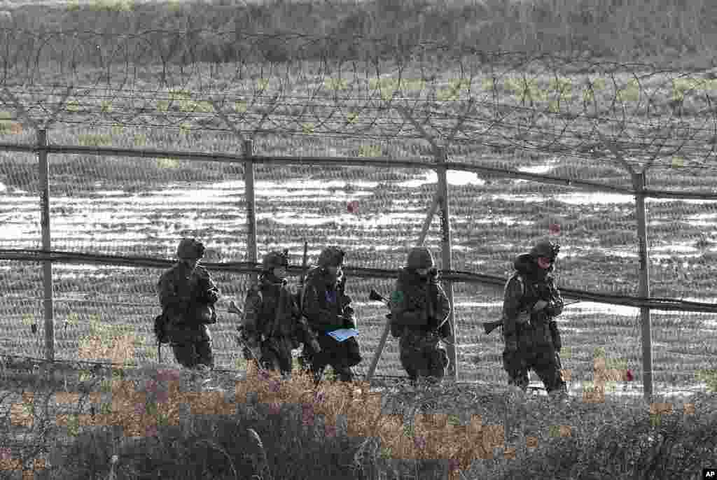 South Korean Army soldiers patrol along a barbed-wire fence near the border village of Panmunjom in Paju, South Korea, March 11, 2013. 