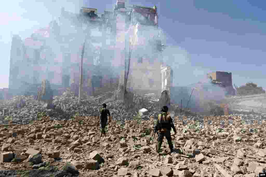 Houthi rebel fighters inspect the damage after an airstrike reportedly carried out by the Saudi-led coalition targeted the presidential palace in the Yemeni capital Sana'a.