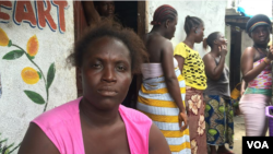 Ebola survivor Finda Fallah sits in front of her new room in West Point, Monrovia, Liberia. As the West African country begins to recover from the crisis, many women are struggling to face a future without their husbands or fathers – the main breadwinners in their families. (Benno Muchler/VOA)