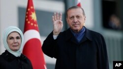 Presiden Turki Recep Tayyip Erdogan dan istrinya, Emine, melambai kepada pendukungnya di Ankara, Senin (17/4). 