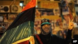 A Libyan woman carrying the flag of the old Libyan monarchy flashes a V for victory sign during a gathering against Libyan leader Moammar Gadhafi at Revolution Square in Benghazi, May 17, 2011