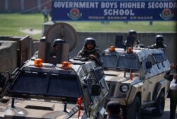 Pasukan keamanan India berjaga dengan kendaraan lapis baja di luar sebuah sekolah setelah tersangka militan menembak mati dua guru di Srinagar, 7 Oktober 2021. (REUTERS/Danish Ismail)