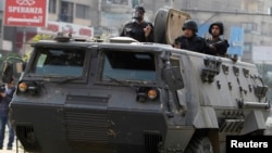 Riot police look from their armoured personnel vehicle during clashes with supporters of Muslim Brotherhood and ousted Egyptian President Mohamed Mursi at Nasr City district in Cairo, Jan. 3, 2014. 