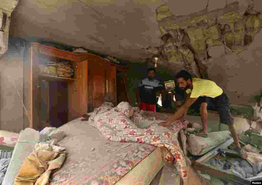 Palestinians inspect a bedroom inside a house which police said was destroyed in an Israeli air strike in Gaza City July 14, 2014.