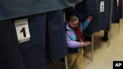 Seorang warga keluar dari bilik suara setelah mengikuti pemilihan umum di salah satu TPS di Milan, Italia (24/2).