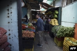 Jairo Colmenares a Venezuela's subway employee asks for prices of vegetables at the market in the west of Caracas, Dec. 29, 2018.