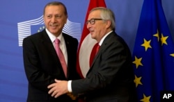 FILE - Turkish President Recep Tayyip Erdogan, left, is greeted by European Commission President Jean-Claude Juncker prior to a meeting at EU headquarters in Brussels, Belgium, Oct. 5, 2015. Observers warn of an increasingly assertive Turkish president who is well aware of Turkey's importance to Europe.