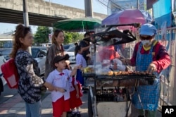 Schoolchildren gather around street vendors outside their school in Bangkok, Thailand, Nov. 1, 2018. A report by the United Nations Food and Agricultural Organization released Friday says some 486 million people are malnourished in Asia and the Pacific, a U.N. report found.