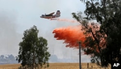 FILE - An air tanker drops a load of fire retardant while fighting a large grass fire, July 27, 2015, in Elverta, Calif.